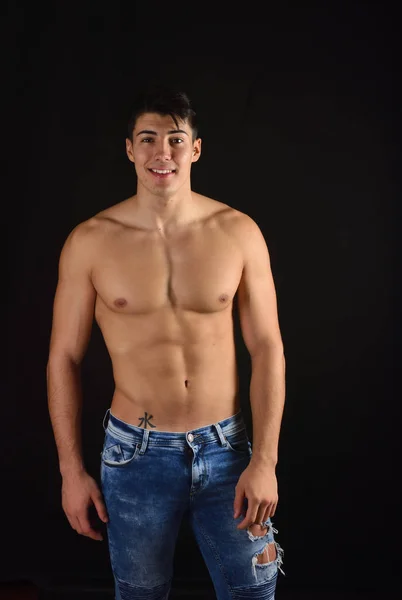 Ritratto di giovane uomo con busto nudo con jeans sul retro nero — Foto Stock