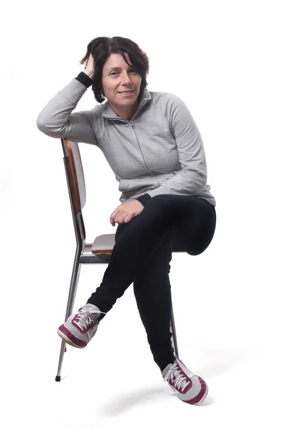 Porträtt av en kvinna som sitter på en stol i vit bakgrund — Stockfoto