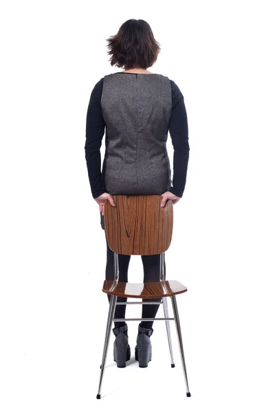 Bakifrån av en kvinna med en stol i vit bakgrund — Stockfoto