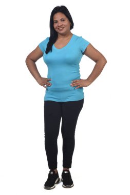  Beyaz arka planda spor giyimli, elleri kalçasında bir kadın.