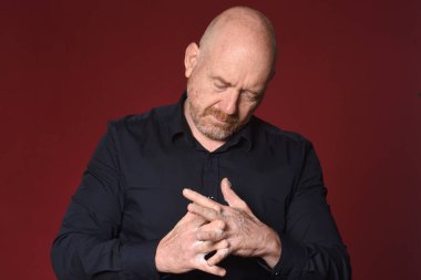 Adam ellerini kırmızı arka planda yıkıyor, elleri parmaklarının arasında