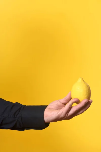 Mão Segurando Uma Fruta Limão Fundo Amarelo — Fotografia de Stock