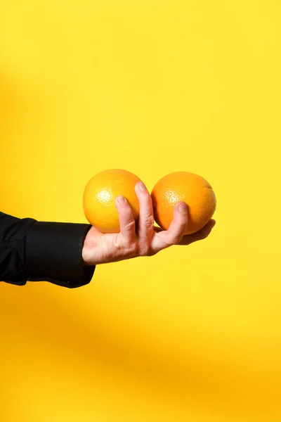Mão Segurando Uma Fruta Laranja Fundo Amarelo — Fotografia de Stock