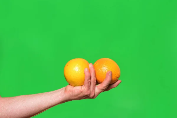 Mão Segurando Uma Fruta Duas Laranjas Fundo Verde — Fotografia de Stock