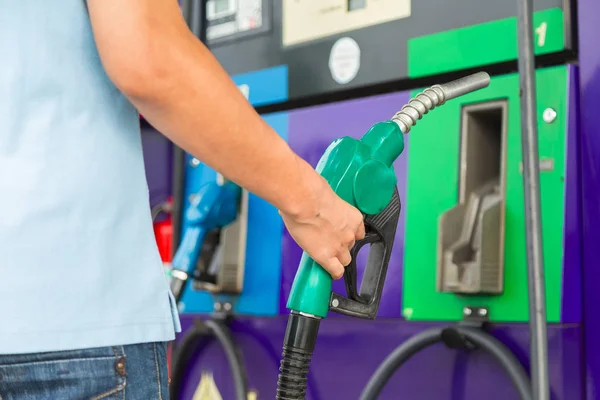 Hombre mantenga la boquilla de combustible para agregar combustible en el coche en la gasolinera . — Foto de Stock