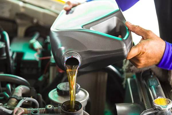 Mecánico de automóviles reemplazando y vertiendo aceite fresco en el motor en la principal —  Fotos de Stock