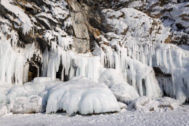 Baykal Gölü, soğuk kış günlerinde. Büyük buz kabuklu güzel buzlu kayalar. Olkhon Adası 'nın buzlu kıyılarında uzun buz sarkıtları.