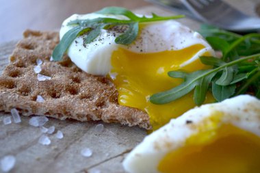 Tahta bir masada roka ile tam tahıllı ekmeğin üzerinde haşlanmış yumurta. Lezzetli ve sağlıklı kahvaltı..