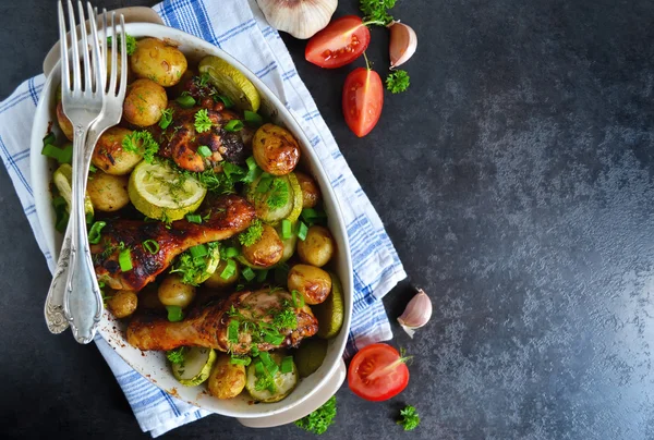 Запеченный картофель с курицей и овощами на черном фоне — стоковое фото