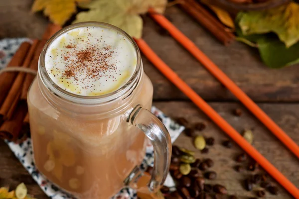 Hot latte with pumpkin, cinnamon and almonds on wooden backgroun — Stock Photo, Image