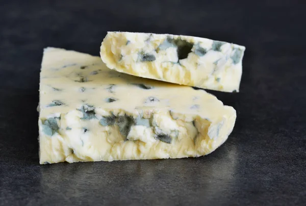 Fatia de queijo azul em um fundo preto — Fotografia de Stock