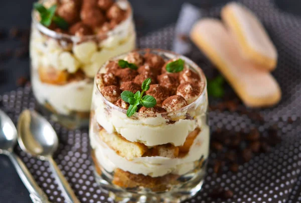 Classic tiramisu in a glass jar on black background — Stock Photo, Image