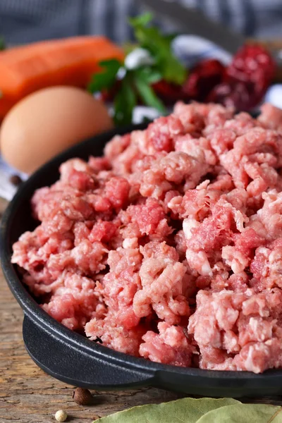 Carne crua em uma frigideira de ferro fundido em um fundo de madeira — Fotografia de Stock