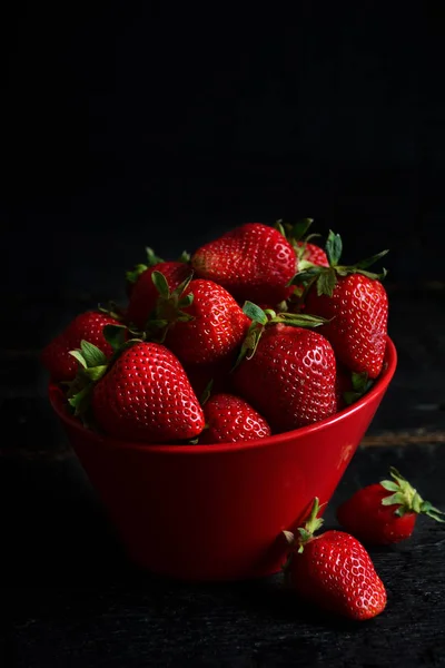 Juicy, fresh strawberries in a dish on a black background — Stock Photo, Image