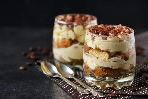 Tiramisu clássico em um frasco de vidro em um fundo preto — Fotografia de Stock