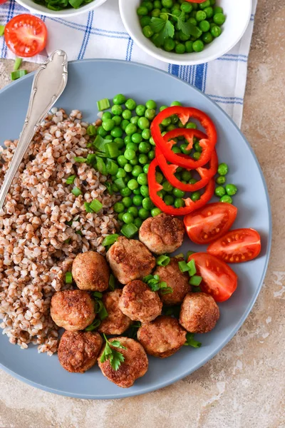 Buckwheat with meatballs and vegetables on a concrete background — Stock Photo, Image