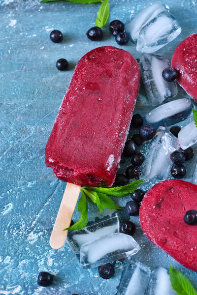 Blueberry ice cream on a stick with a blackberry. 