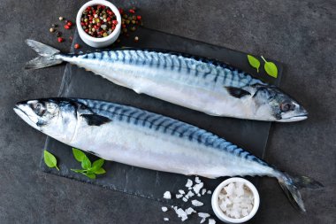 Fresh, raw mackerel with spices on a black concrete background clipart