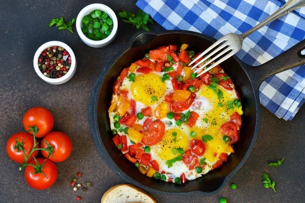 Uova con pomodori, pepe e piselli verdi in una padella . — Foto Stock