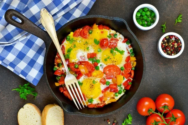 Ägg med tomater, paprika och gröna ärtor i en stekpanna. — Stockfoto