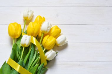 T altında boşluk ile beyaz bir arka planda sarı ve beyaz laleler