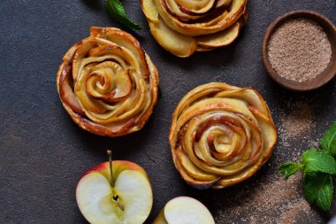 Koyu beton bir sırt üzerinde puf böreğinde pişirilmiş elma gülleri tabağı.