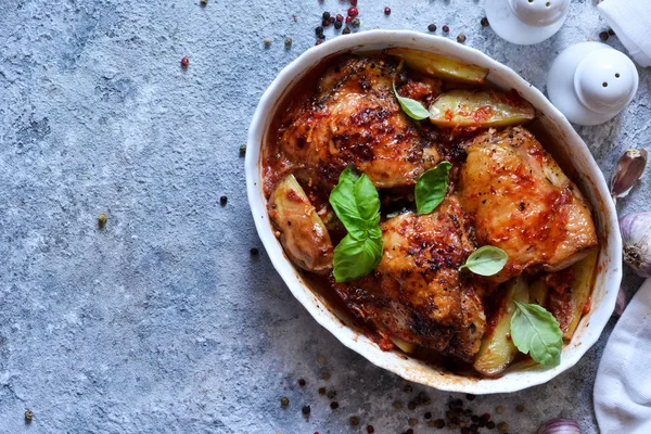 Gebackene Hähnchenschenkel mit Kartoffeln, Tomatensauce und Basilikum auf einem — Stockfoto