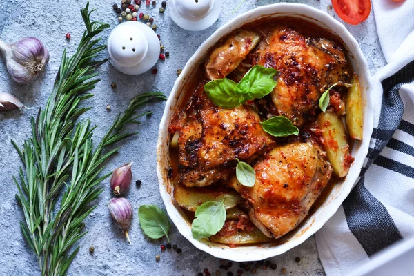 Fırında tavuk budu, patates, domates sosu ve fesleğen. 