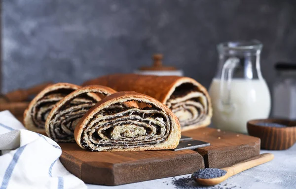 Rosy roll with poppy seeds and milk on a concrete background. — Stock Photo, Image