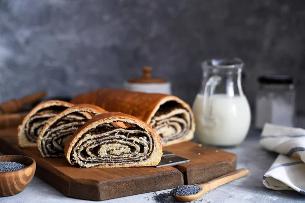 Rosy roll with poppy seeds and milk on a concrete background. — Stock Photo, Image