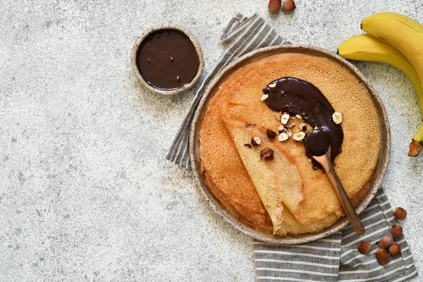 Crepes with chocolate paste, bananas and nuts