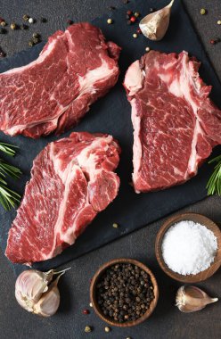 Taş bir tahtanın üzerinde çiğ mermer biftek. Baharatlar, yemekler. 