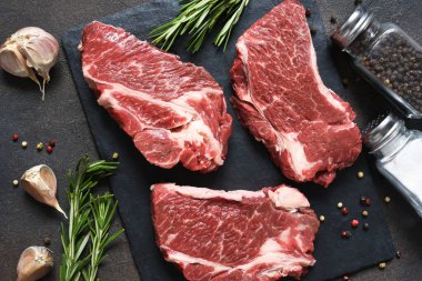 Taş bir tahtanın üzerinde çiğ mermer biftek. Baharatlar, yemekler. 