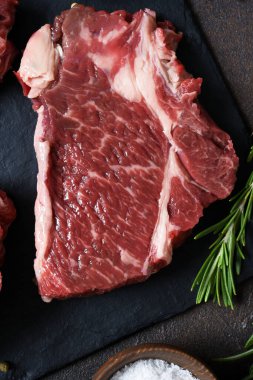 Taş bir tahtanın üzerinde çiğ mermer biftek. Baharatlar, yemekler. 
