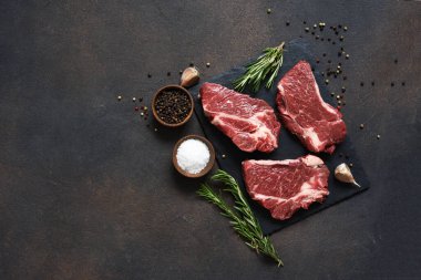 Taş bir tahtanın üzerinde çiğ mermer biftek. Baharatlar, yemekler. 
