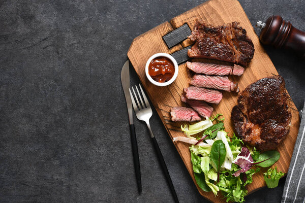 Grilled marbled beef steak with salad on a wooden board 