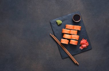 Taş bir tahtanın üzerinde somon ve avokado ile suşi. Suşi menüsü.