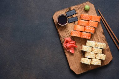 Ahşap bir tahtada servis edilen farklı suşi türleri. Suşi menüsü.