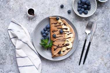 Kahvaltıda muz, çikolata sosu ve yaban mersinli krep..