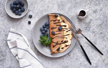 Kahvaltıda muz, çikolata sosu ve yaban mersinli krep..