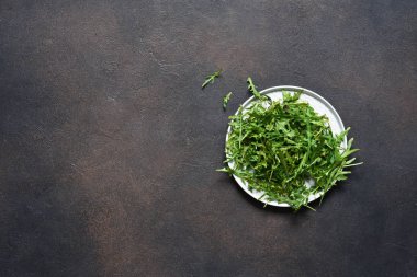 Taze, yeşil roka salatası koyu taştan bir arka planda. 