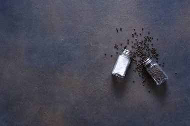 Beton bir arka planda cam kavanozdaki tuzlu ve biberli bezelyeler. Gıda arka planı, baharatlar, üst manzara..