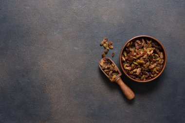 Koyu beton arka planda bir tabakta güzel kuru üzümler ve metin için yer var. Yukarıdan görüntüle.