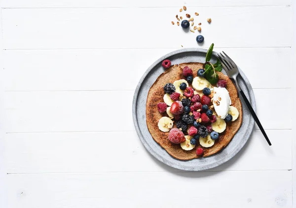 Crepe with berries and yogurt for breakfast. Breakfast on the kitchen table top view.