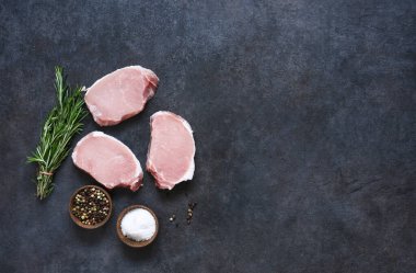 Siyah beton arka planda taze domuz bifteği. Yemek pişirmek için gerekli malzemeler.