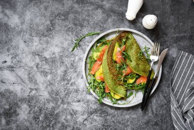 Mutfak masasında ıspanaklı, somonlu ve peynirli krep. Yukarıdan görüntüle.