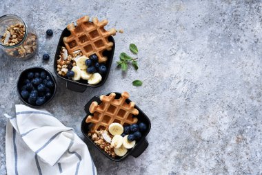 Kahvaltıda yoğurtlu Belçika waffle 'ı, granola, muz ve yabanmersini. Yukarıdan görüntüle.