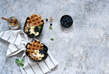 Kahvaltıda yoğurtlu Belçika waffle 'ı, granola, muz ve yabanmersini. Yukarıdan görüntüle.