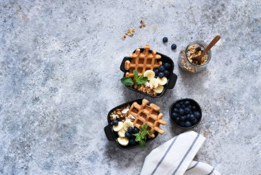 Kahvaltıda yoğurtlu Belçika waffle 'ı, granola, muz ve yabanmersini. Yukarıdan görüntüle.