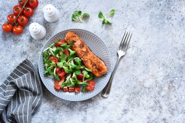 Izgara somon dilimi ve mutfak masasında domatesli salata. Restoran için menü..